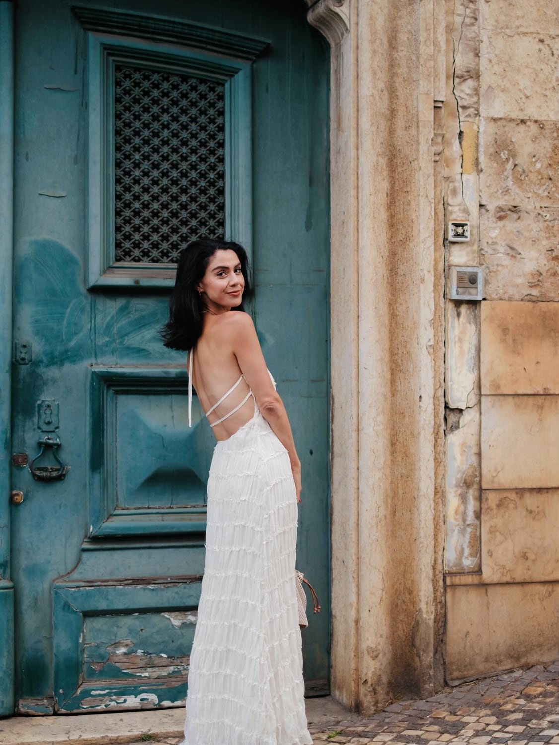 Kimia in a white dress beside a weathered blue Lisbon door
