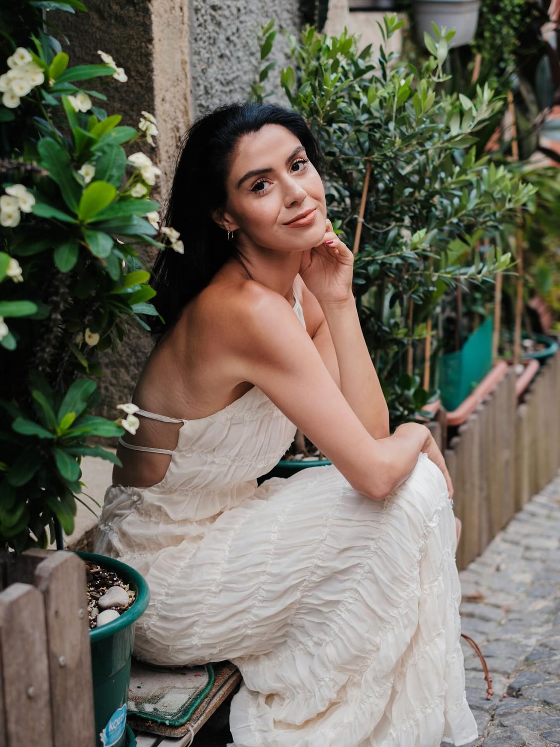 Kimia seated among greenery in a white dress