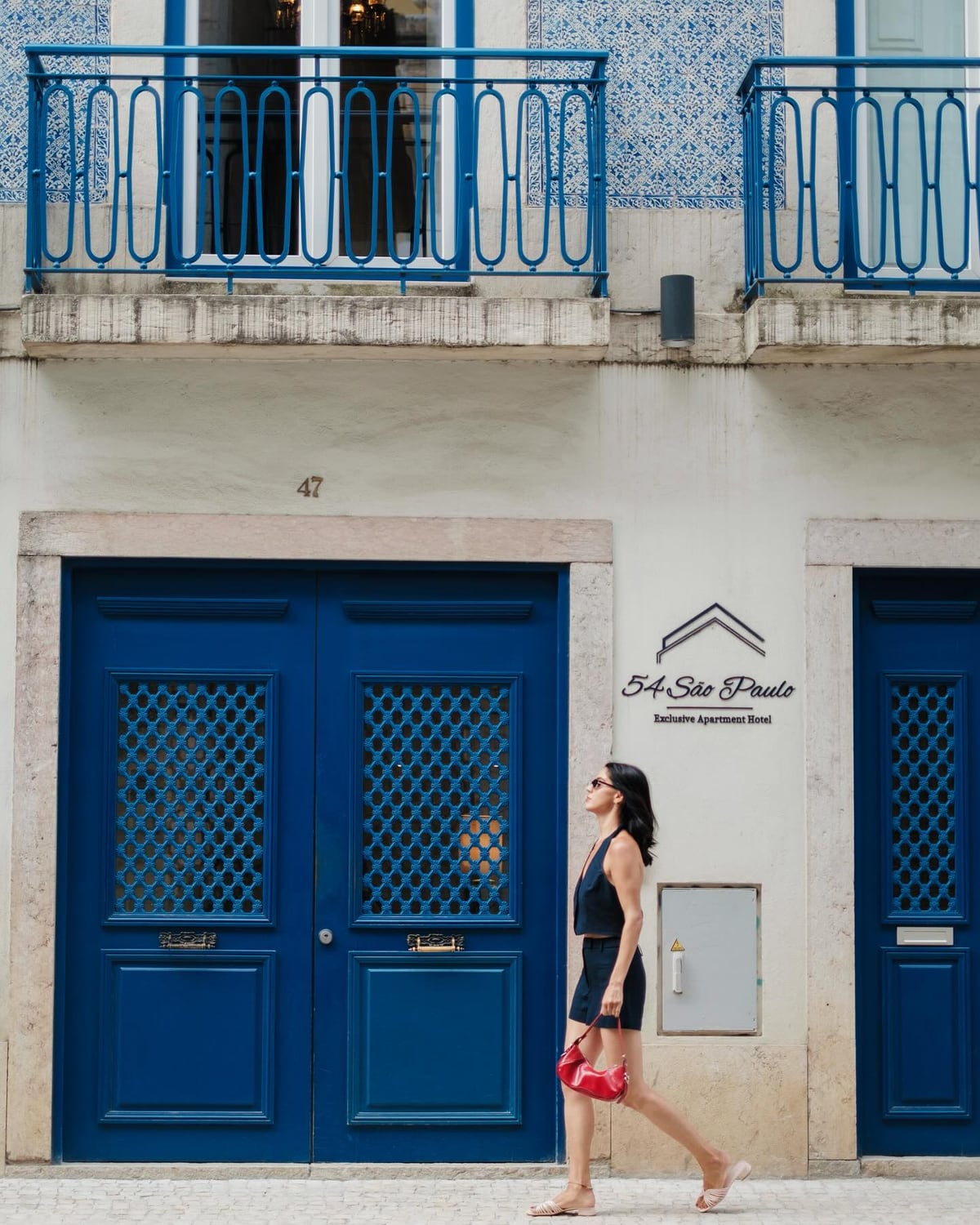 Kimia walking past vivid blue doors in Lisbon