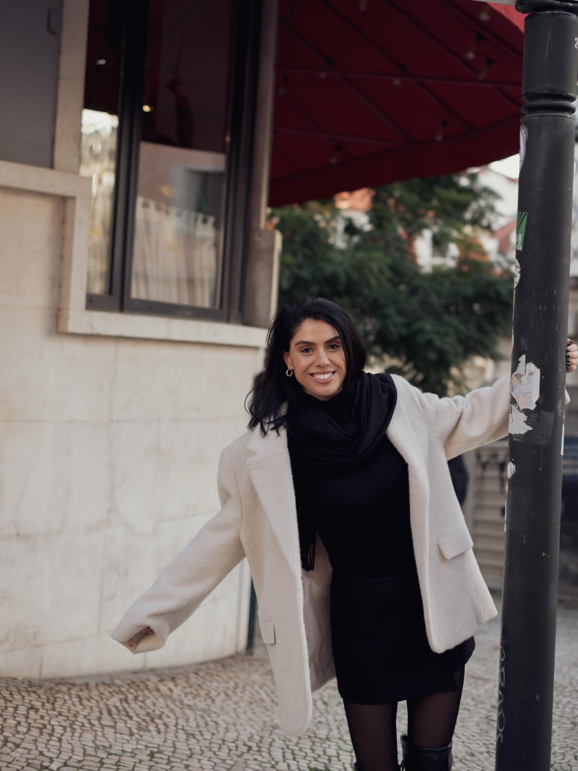 Kimia smiling beneath a red awning in Lisbon